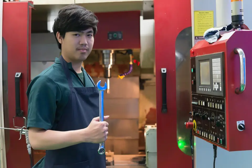 ช่างประจำเครื่อง CNC ถือประแจหน้าเครื่องจักรในโรงงาน